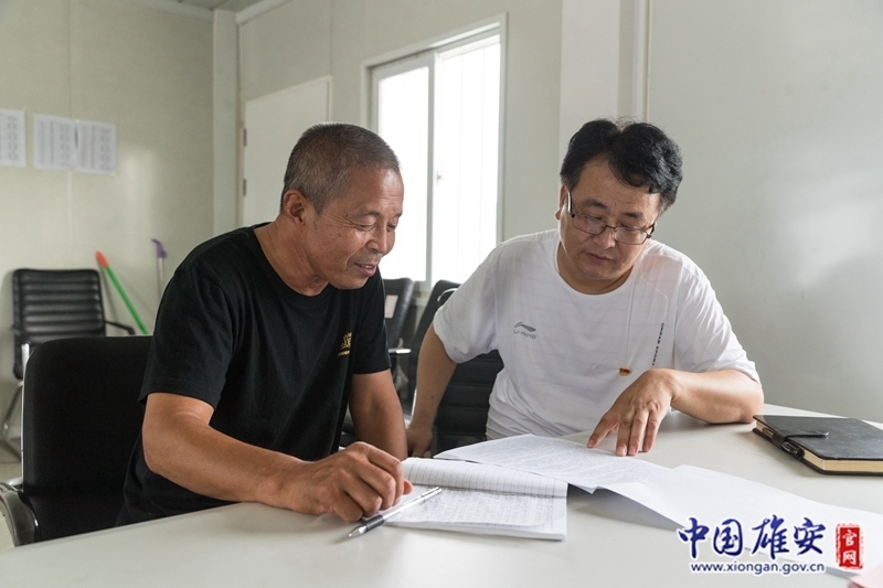 在大張堡村綜合服務(wù)站內(nèi)，擺放著幾張辦公桌和幾張簡(jiǎn)易床。工作認(rèn)真、兢兢業(yè)業(yè)是同事對(duì)王占忠的評(píng)價(jià)。下班后，王占忠還會(huì)與其他征遷村的駐村黨員干部、村“兩委”干部進(jìn)行交流探討，借鑒他們的經(jīng)驗(yàn)。圖為王占忠與大張堡村原村委會(huì)主任交流學(xué)習(xí)。中國(guó)雄安官網(wǎng)記者牛思佳 攝